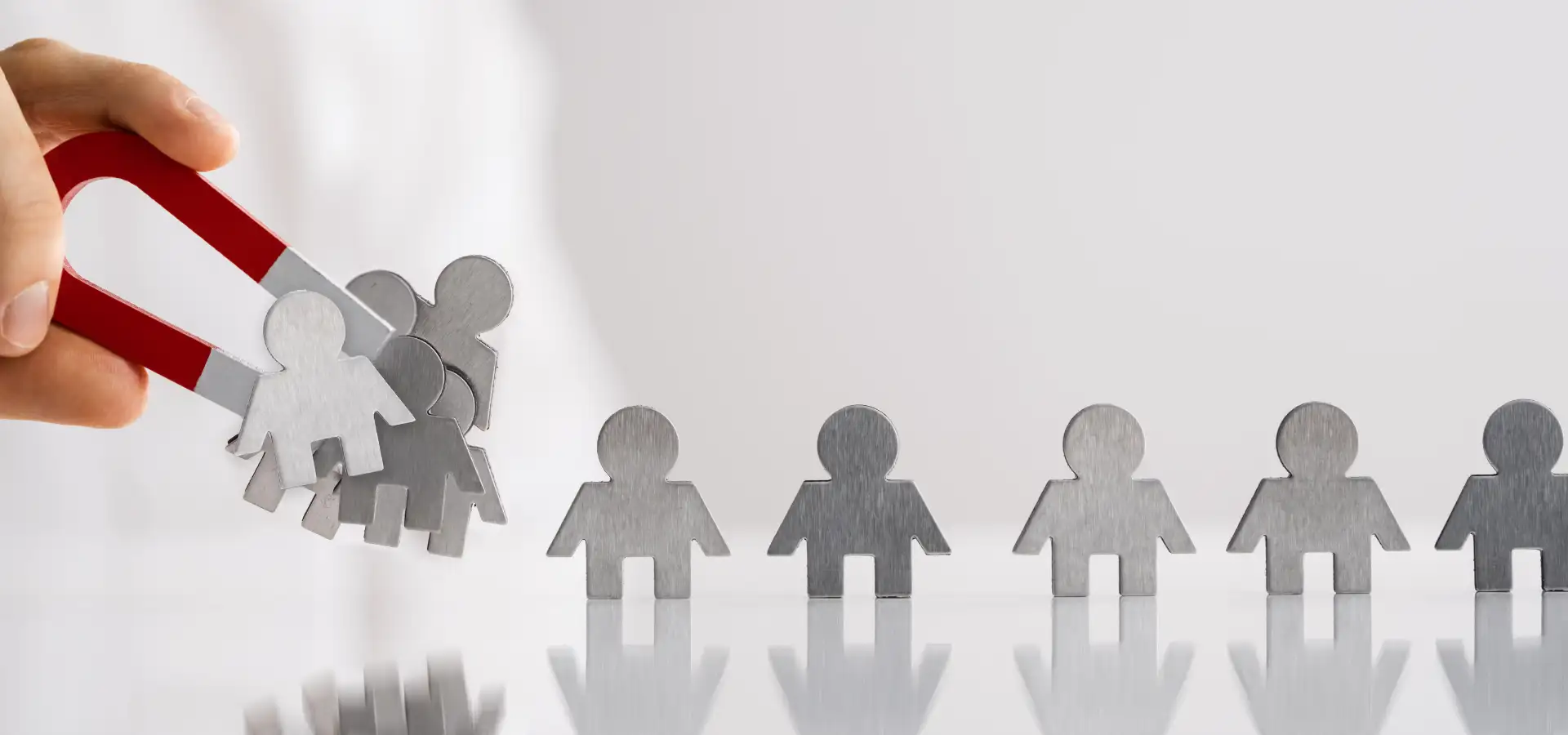 Aimant attirant des silhouettes de papier, métaphore de l'attraction client en web marketing.
